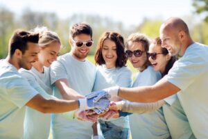 group of volunteers putting hands on top in park