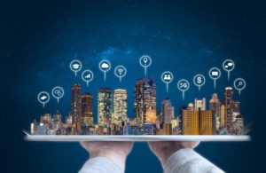 Hand holding digital tablet with modern buildings hologram and technology icons. Smart city, internet and networking smart technology