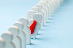 Staff recruitment. Headhunting. Many employees and the choice of a leader from the crowd. HR. A lot of white businessman and one in a red tie on a blue background