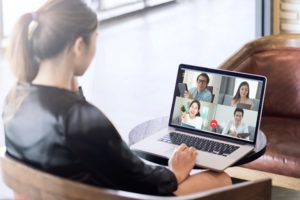 Back view of business woman talking about sale report in video conference. Asian team using laptop and tablet online meeting in video call.Working from home, Working remotely and Social isolation.