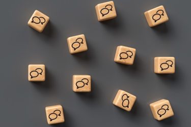 many cubes with speech bubble icons and smartphone on wooden bac